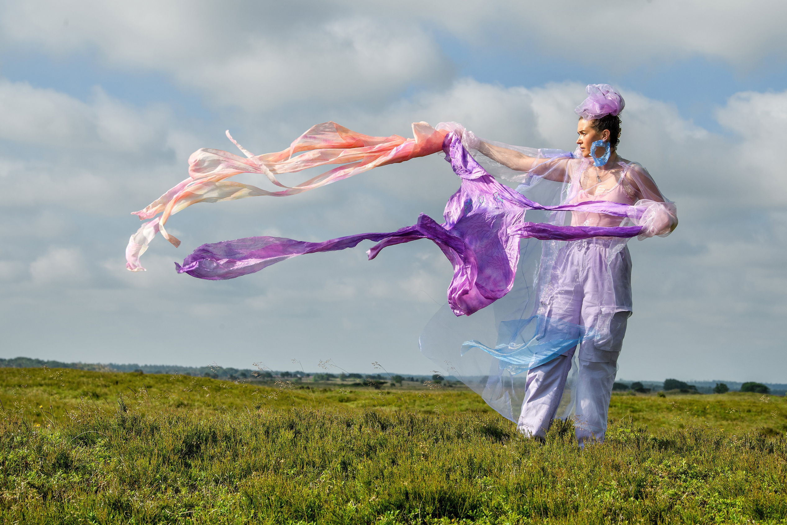 Kunstværk af kvinde på græsmark med flyvende tørklæder